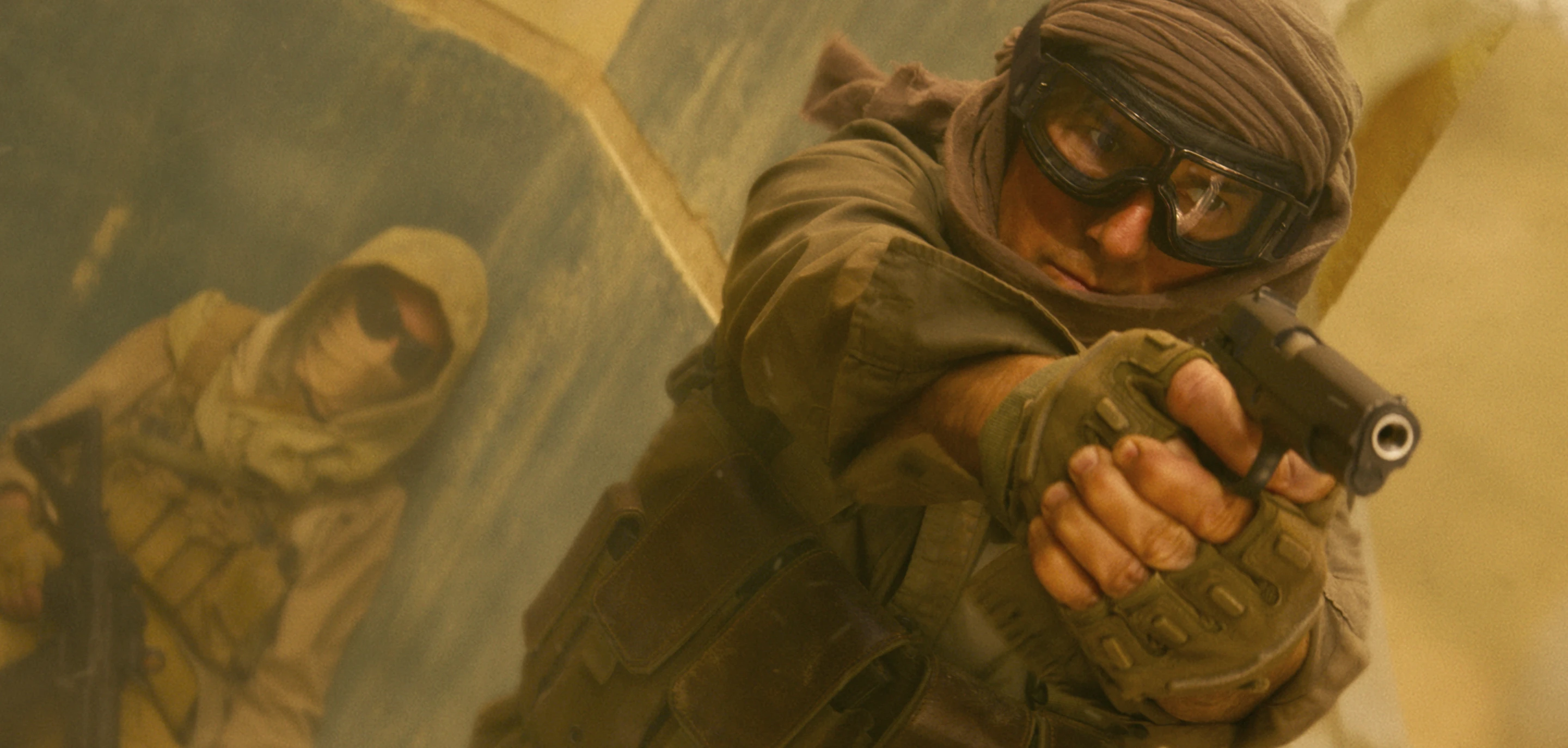 Tom Cruise pointing a gun in a sandstorm