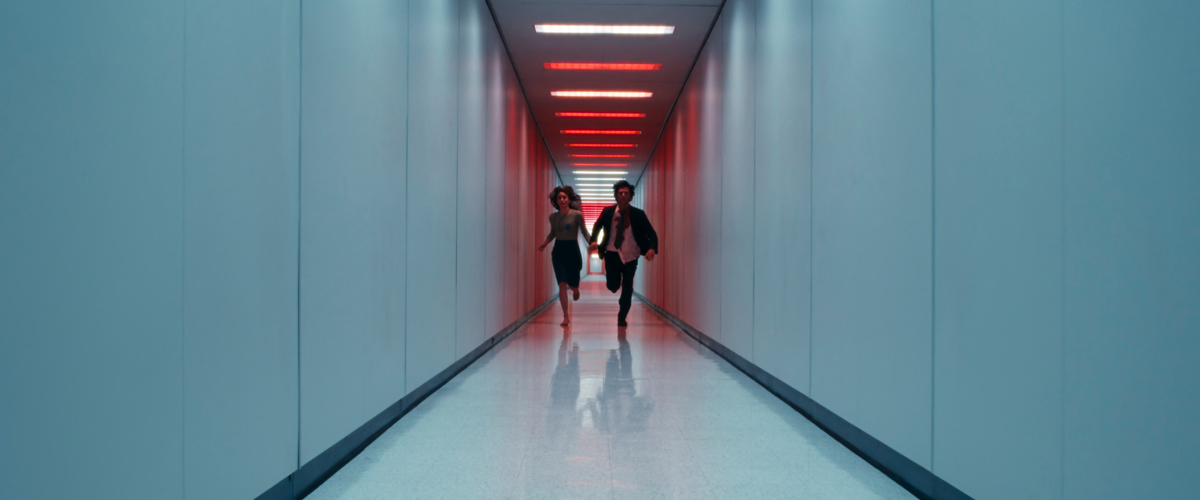 Britt Lower and Adam Scott running down a corridor